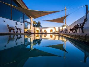 a pool of water with chairs and a building at Merwenstein - Farm House, Cottages, Studio-Units in Bonnievale