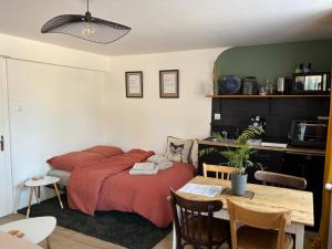 a bedroom with a bed and a table and a kitchen at le Studio Balnéo des Cocons de Mel in Quinssaines
