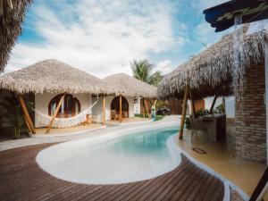 a resort with a swimming pool and thatched huts at Villa Mia - Praia do Preá in Prea