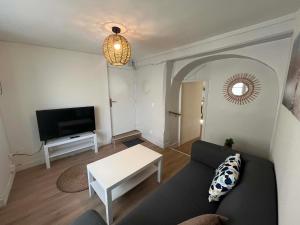a living room with a couch and a tv at L'écrin pure in Falaise