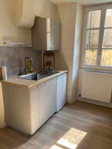 a kitchen with white cabinets and a sink and a window at L'écrin pure in Falaise
