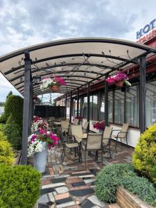 a pergola with chairs and flowers on a patio at Hotel Mimoza in Libusza