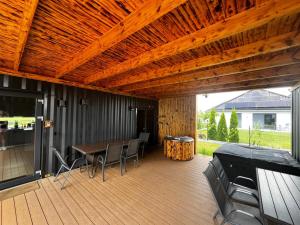 a patio with a table and chairs and a wooden ceiling at Apartament Glamour II Kleszczów in Łękińsko