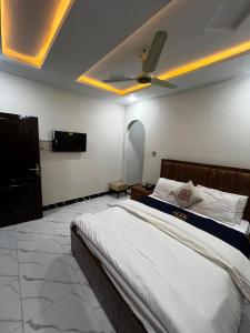 a bedroom with a bed with a ceiling fan at Abu Khalid By MZ Hotels & Restaurant in Mingāora