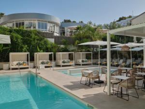 a hotel pool with tables and chairs and umbrellas at BQ Paguera Boutique Hotel - Adults Only in Paguera