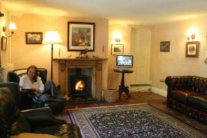 a woman sitting in a chair in a living room with a fireplace at Staghunters Inn Hotel in Countisbury
