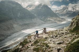 two people riding bikes on a mountain trail near a river at Golfhotel Riederhof in Riederalp