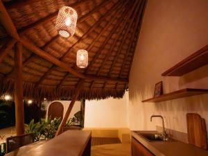 a kitchen with a straw ceiling with two lights and a sink at Villa Mia - Praia do Preá in Prea