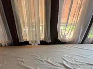 a bed in front of a window with white curtains at Moratuwa suburban oasis in Moratuwa