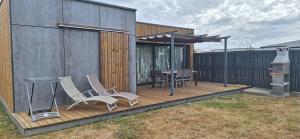 a wooden deck with chairs and a table on it at O Ptit home in Saint-Vincent-sur-Jard