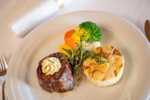 a plate of food with meat and vegetables on it at Golfhotel Riederhof in Riederalp +56 photos