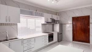 a white kitchen with a sink and a refrigerator at Saob Property in Germiston