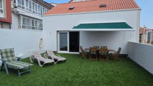 a patio with chairs and a table and a green roof at Casa del Arenal - Laxe in Laxe