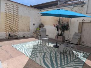 two chairs and an umbrella on a patio at Gîte LM in Bourbonne-les-Bains