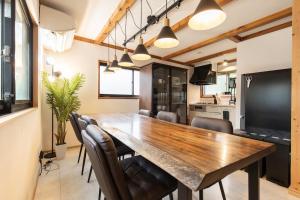 a dining room with a large wooden table and chairs at 愛犬と泊まれる一棟貸しviilaはBBQグリル無料利用可能サーフィンや釣りの拠点として in Kashima