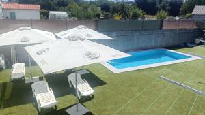 two white umbrellas and chairs next to a swimming pool at Hostel Boente in Boente