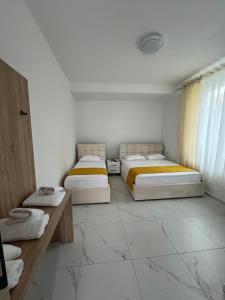 two beds in a room with white tile floors at Aer Rooms Peshkopi in Peshkopi