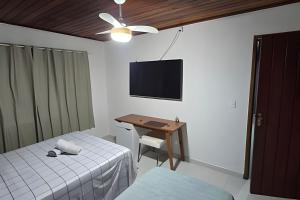 a bedroom with two beds and a desk and a television at Sossego Real: Casa Solo C/ Banheira Ofuro in Ilhabela
