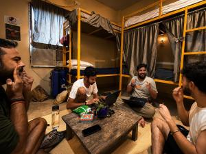 a group of men sitting in a room with bunk beds at The Third Space Varanasi in Rāmnagar