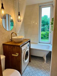 a bathroom with a tub and a sink and a washing machine at Taevaskoja külaliskorter in Taevaskoja