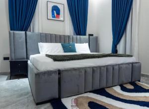 a bedroom with a large bed with blue curtains at Rosedale luxury apartment in Ashouman