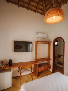 a bedroom with a desk and a television on the wall at Villa Mia - Praia do Preá in Prea