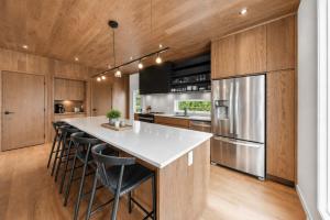 a kitchen with wooden cabinets and a large island with bar stools at Mountain - Sauna - Camp de base du Massif in Saint-Philémon