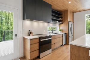 a kitchen with black cabinets and a large window at Mountain - Sauna - Camp de base du Massif in Saint-Philémon