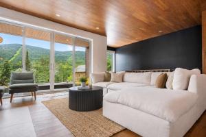 a living room with a white couch and a large window at Mountain - Sauna - Camp de base du Massif in Saint-Philémon +25 photos