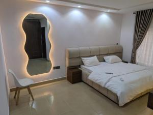 a bedroom with a bed and a chair and a mirror at Kroft Residence in Lekki