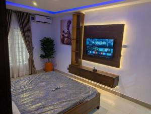 a bedroom with a bed and a flat screen tv at Kroft Residence in Lekki