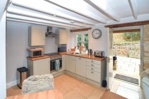 a kitchen with white cabinets and a clock on the wall at 1 Bed in Moreton -in- Marsh oc-53420 in Blockley