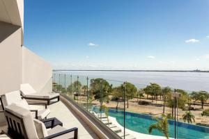 a balcony with chairs and a view of the water at Marriott Corrientes in Corrientes