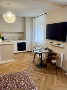 a living room with a table and a kitchen at Nuit Céleste Studio élégant avec parking Centre Morteau in Morteau