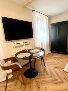 a living room with a table with chairs and a flat screen tv at Nuit Céleste Studio élégant avec parking Centre Morteau in Morteau