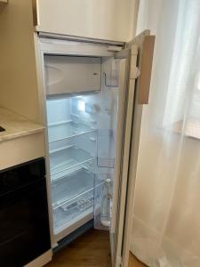 an empty refrigerator with its door open in a kitchen at Nuit Céleste Studio élégant avec parking Centre Morteau in Morteau +9 photos