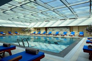 a large swimming pool with blue lounge chairs in a building at Four Points by Sheraton Shanghai, Daning in Shanghai