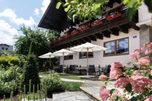 a building with tables and umbrellas in a garden at Landhaus Steiner in Altenmarkt im Pongau