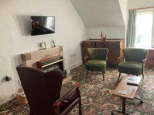 a living room with two chairs and a fireplace at Vintage Retreat in Kingussie