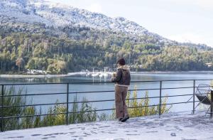 a man standing on a balcony looking at a lake at Puerto Manzano Boutique Hotel in Villa La Angostura