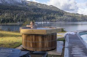 a woman sitting in a hot tub next to a lake at Puerto Manzano Boutique Hotel in Villa La Angostura