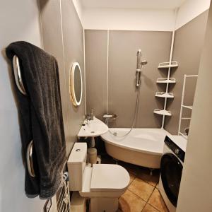 a bathroom with a tub and a toilet and a sink at Old town boutique apartaments in Ukmergė +12 photos