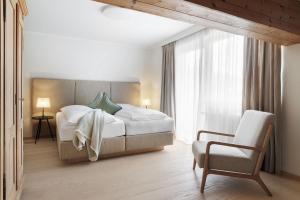 a bedroom with a large bed and a chair at Landhaus Steiner in Altenmarkt im Pongau