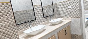 a bathroom with two sinks and two mirrors at فلل فاخرة للإيجار صلالة Salalah Villas in Salalah