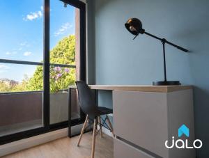 a desk with a lamp and a chair in front of a window at Well 100 by JALO in Bogotá
