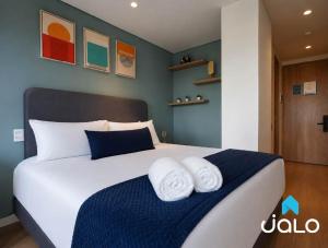 a bedroom with a large bed with towels on it at Well 100 by JALO in Bogotá