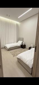 two beds in a bedroom with white walls and curtains at Elite stay 1 in Buraydah