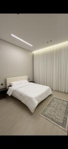 a bedroom with a large white bed and a rug at Elite stay 1 in Buraydah