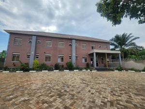 a large pink building with a brick driveway in front of it at Muzinge inn in Kagolomolo
