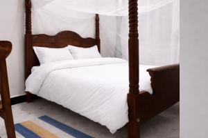 a bedroom with a four poster bed with white sheets at Muzinge inn in Kagolomolo +13 photos